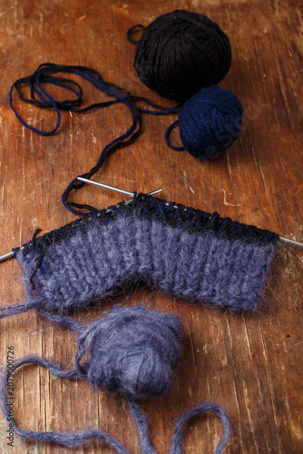 Quadro su tela Knitting needles, dark blue mohair and black acrylic yarn balls on old wooden table background