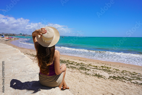 Young woman sitting enjoying view of Pajucara beach, Maceio, Brazil