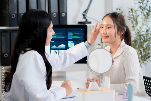Asian woman doctor touching face of patient in clinic and discussing skin analysis on computer screen with ai technology, dermatologist examining facial beauty and consultation for health skin care.