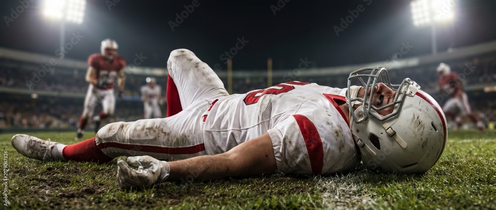 Fototapeta premium Injured American football player lying on field after hard game collision. Concept of sports injury, player safety, football collision, medical response and game risk. Banner