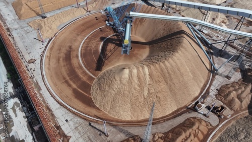 Fotografie Circular stockyard with stacker reclaimer operating on sand and gravel storage s