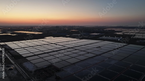 Fotografie Salt evaporation ponds in grid pattern during sunset with reflective water surfa
