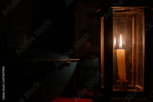 Foto Burning candle beside old cast iron pot inside a traditional peasant house at night