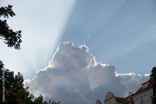 Photography Sun rays bursting from behind dramatic storm clouds above the city skyline