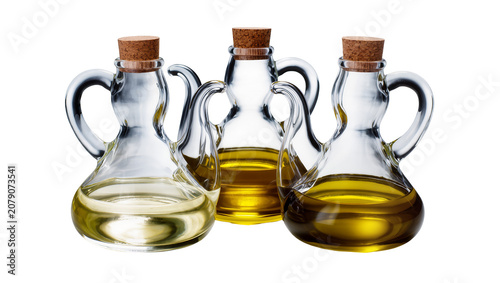Photos Isolated three glass cruets with corks containing different shades of cooking oi