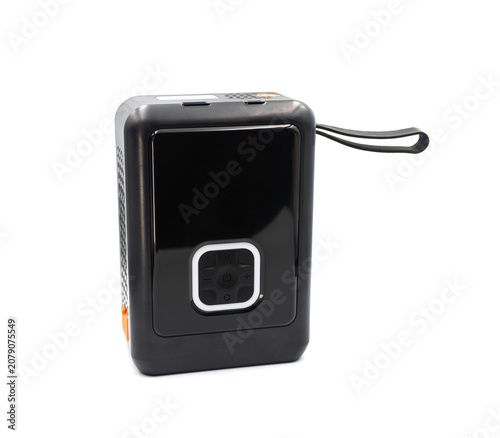 Multi-functional black emergency car battery booster and digital tire inflator isolated on white. High-tech portable power bank device for automotive start and road assistance.
