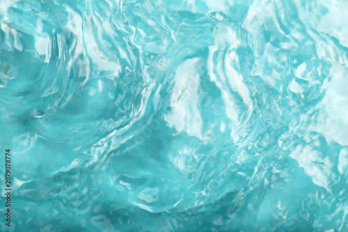 Blue water background. Close-up view of blue water with gentle waves and reflections, showcasing fluid movement and texture of surface in tranquil aquatic environment