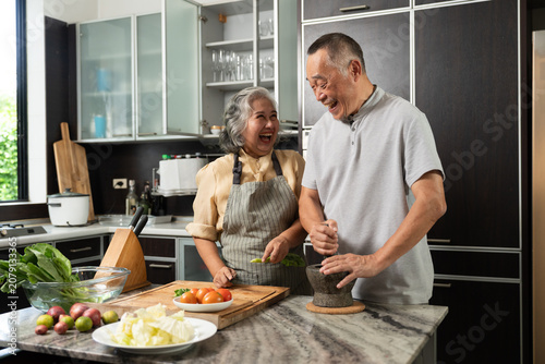 Elderly couple chopping vegetables together in kitchen, representing family bonding, healthy lifestyle, and wellness in cozy indoor environment with natural daylight, modern design, and cheerful