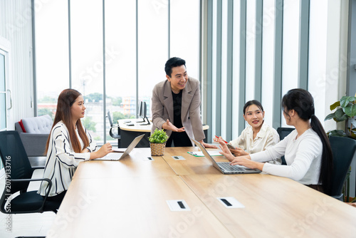 A group of professionals engage in a collaborative meeting in a modern office. The scene highlights teamwork, leadership, dynamic communication in a productive corporate environment.