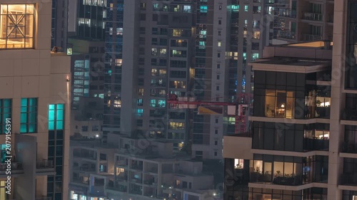 Illuminated glass facade night timelapse captured perfectly over Dubai. The sheer vertical scale of the glass architecture is emphasized by the dark night sky. Busy district.