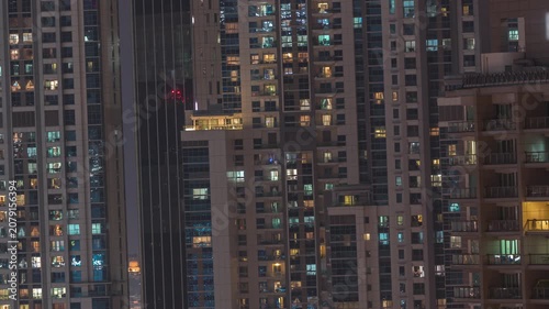 Residential building exterior drone timelapse highlighting the architecture in Dubai. Warm artificial light escapes from countless overlapping residential apartments. Modern styles.