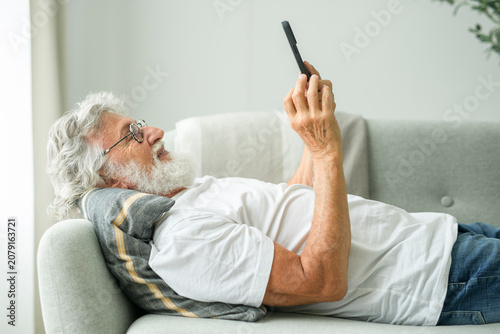 senior men having great time on is home apartment with his cellphone