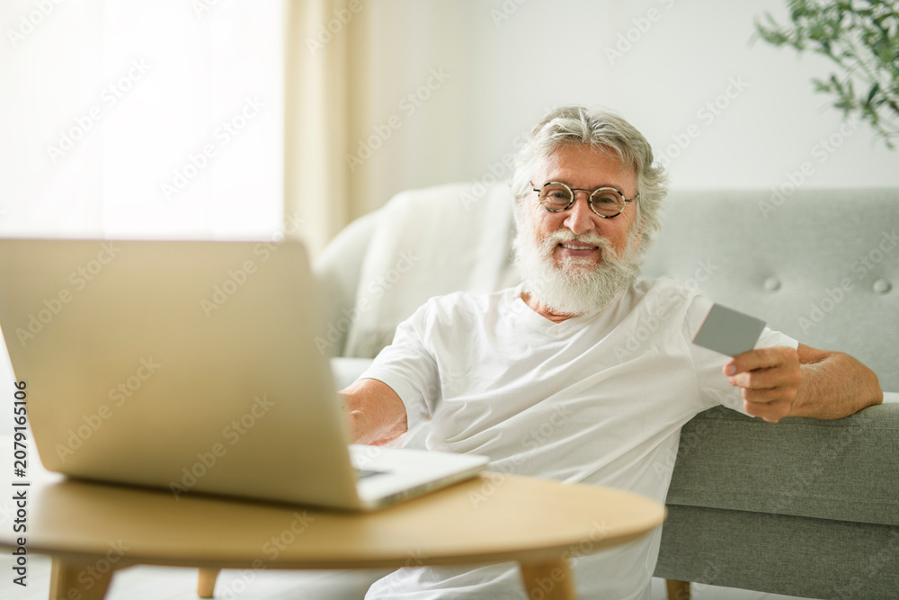 Fototapeta premium senior men using laptop at home apartment with credit card