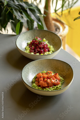 Fresh tuna and salmon bowls with green cucumber and avocado served in a cafe