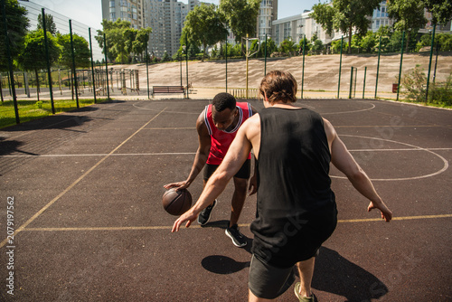 Multiracial friends enjoy summer streetball on an outdoor court