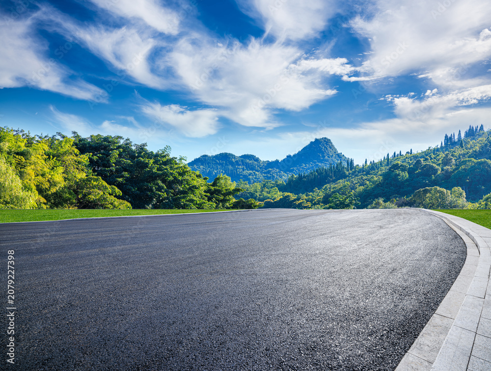 Naklejka premium Empty asphalt road and green mountains under clear blue sky