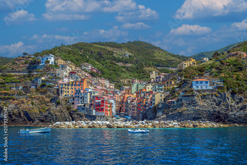 Foto View from the sea of ​​Riomaggiore, one of the  Cinque Terre villages, a steep cascade of pastel houses descending towards a small harbor carved between dark cliffs