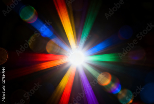 Bright multicolored starburst with lens flare on black background