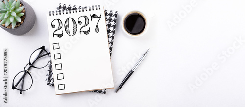 New year resolutions 2027 on desk. 2027 resolutions list with notebook, coffee cup on table. Goals, resolutions, plan, action, checklist concept. New Year 2027 template, copy space