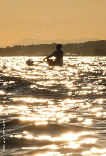 young women  riding  on sup surfing in the sea at sunset