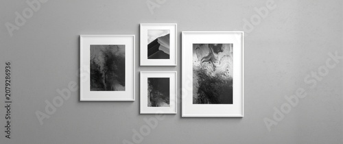 Rectangular picture frames mounted on a neutral grey wall displaying black and white photography