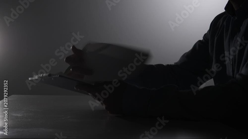 Person's silhouette writing with a pen on a sheet of paper, highlighting concepts of work, legal matters, and business in a dark, focused setting