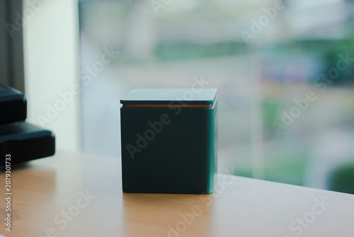 Minimal black gift box mockup on a wooden table with a soft blurred background, ideal for luxury packaging presentations, product branding, premium gift concepts, e-commerce, advertising, and modern m