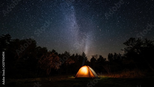 Vertical angle of a campsite glowing warmly under a clear and magnificent starry sky