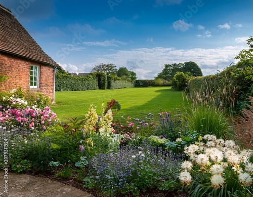 rustic english country garden with charming flowers and green fields