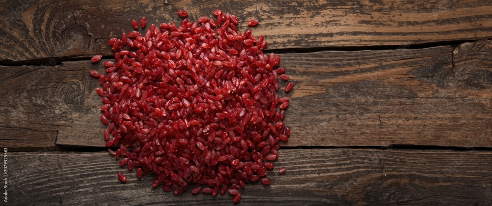 Fototapeta premium Red rice grains arranged on rustic wooden surface