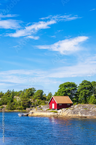 Rote Holzhütte und Bäume an der Küste der Insel Rossö nahe Strömstad, Schweden