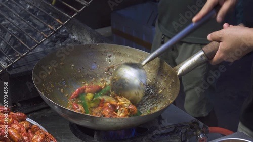 Street vendor is frying shrimps and vegetables in wok