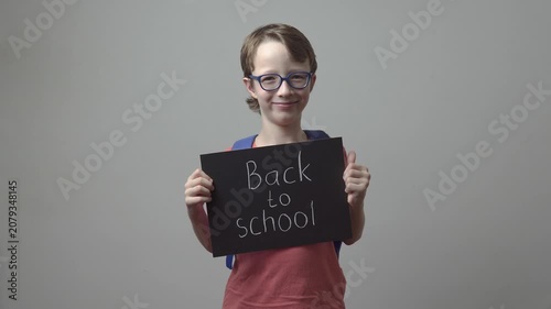School boy in glasses is holding chalkboard. Back to school