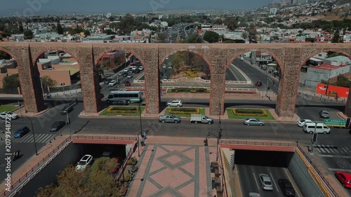 Aerial perspective of iconic stone arches defining Querétaro's historic district with gentle traffic flow and preserved colonial structures creating urban landscape