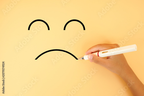 Tableau sur toile Hand drawing a sad face on a pastel background