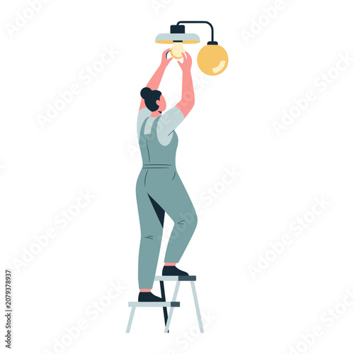 Woman in overalls changing light bulb on stepladder during home maintenance with warm overhead light