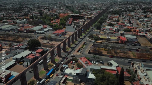Aerial perspective of iconic stone arches defining Querétaro's historic district with gentle traffic flow and preserved colonial structures creating urban landscape