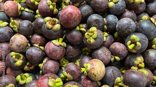 Full frame background of fresh ripe mangosteen fruits on display at a market