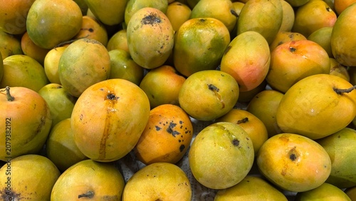 Full frame background of ripe yellow and green mangoes on display at a market