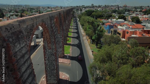 Aerial perspective of iconic stone arches defining Querétaro's historic district with gentle traffic flow and preserved colonial structures creating urban landscape