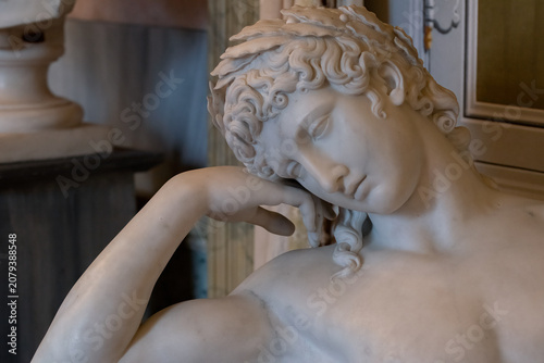 A marble sculpture of a classical figure in repose, emphasizing delicate artistry and serene beauty