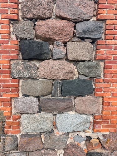 Close-up of a rustic brick and stone wall showcasing a mix of rough textures and natural colors in a traditional masonry pattern