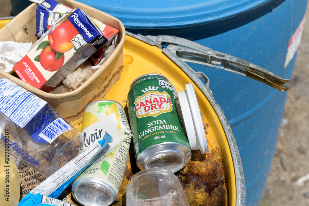 Obraz premium discarded food wrappers and drink containers, including Canada Dry, a carbonated beverage on a metal drum painted yellow in Toronto