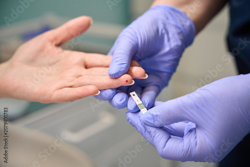 фотографія Medical professional performing finger prick test on patient indoors