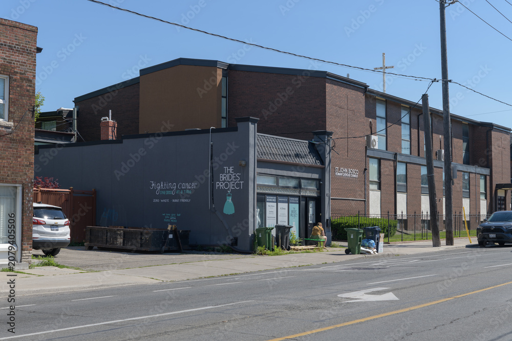 Obraz premium wide view of exterior building and sign of The Brides' Project (82 Rogers Rd) and the rear of St John Bosco Roman Catholic Church (402 Westmount Av), Toronto