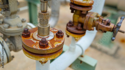 A close-up of a bolt and nut connecting a pipeline shows rust from usage, highlighting maintenance, durability,