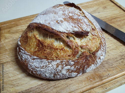 Artisan sourdough bread with a golden crust dusted with flour on a wooden board