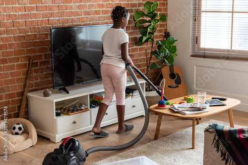 фотографія Child vacuuming cozy living room.