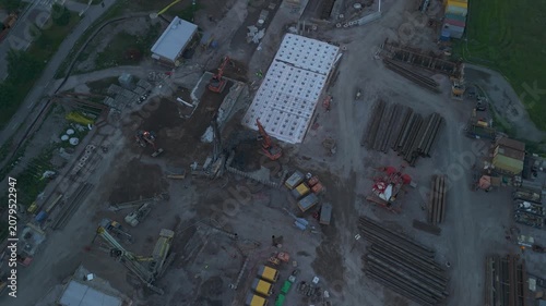 high altitude drone footage of cranes excavators and foundation work in a remote construction area surrounded by untouched natural landscape