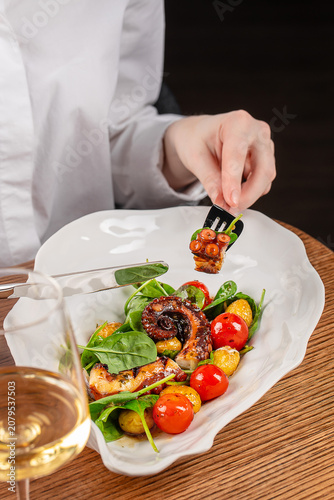 Woman Eating Grilled Octopus Salad in Elegant Restaurant
